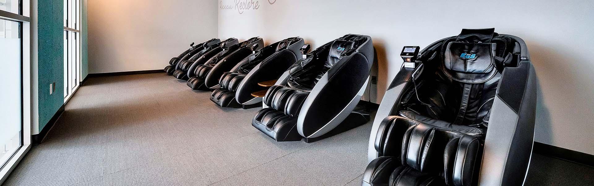 several high tech massage chairs in a well lit and clean eos branded room