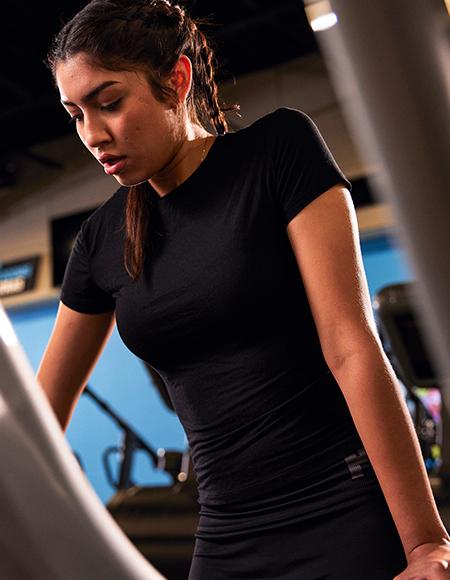 https://eos-wp-prod.azurewebsites.netA woman focused on her workout, leaning on a gym machine