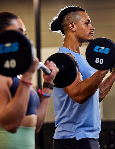 https://eos-wp-prod.azurewebsites.netTwo people performing bicep curls with dumbbells in a gym