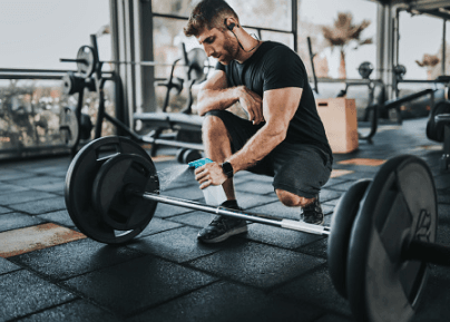 eos gym member kneeling down to wipe and clean a barbell after deadlifting