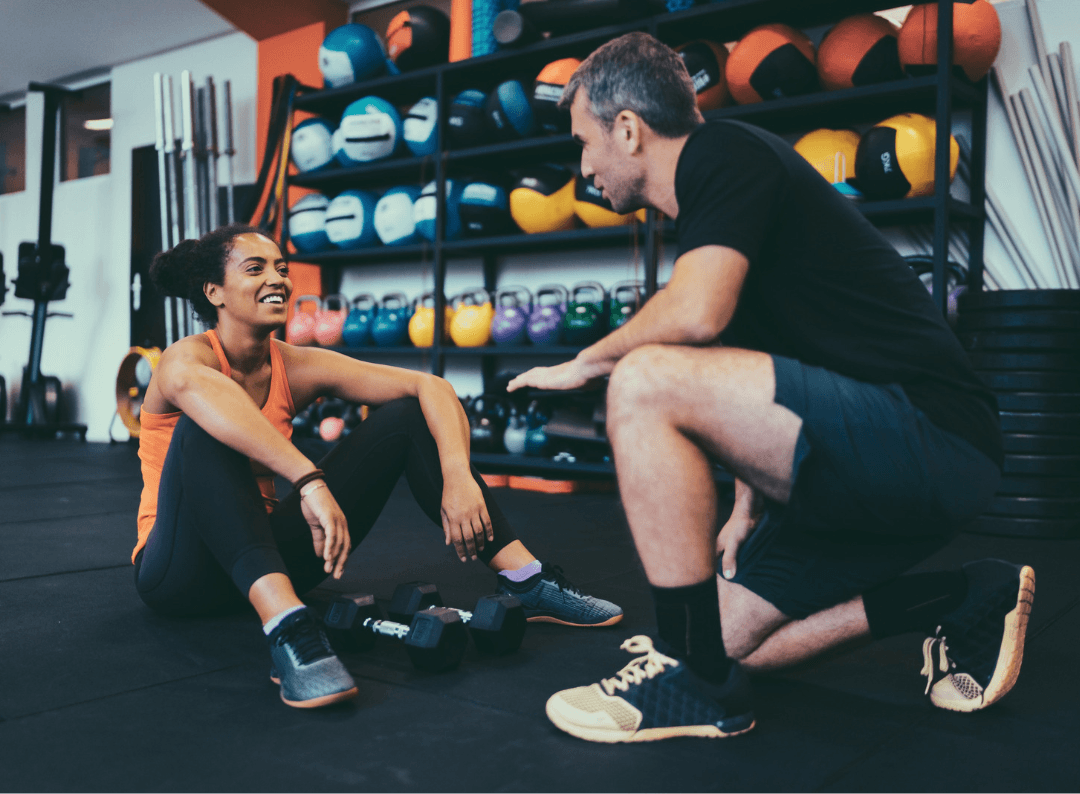 personal trainer kneeling down and helping eos gym member