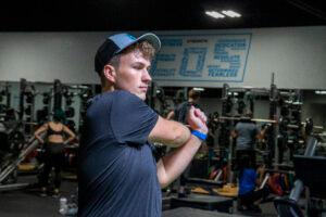 athletic eos gym member stretching arm inside an eos branded gym