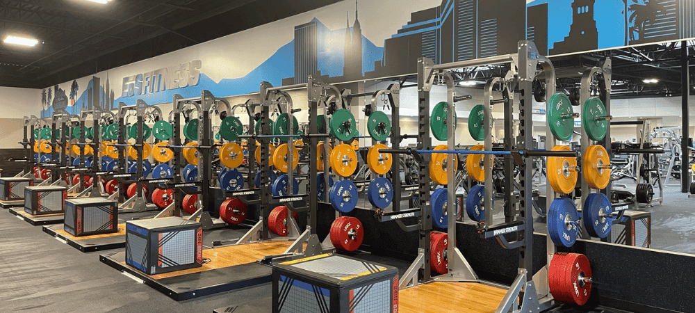 a row of fully equipped power racks in a modern eos fitness gym