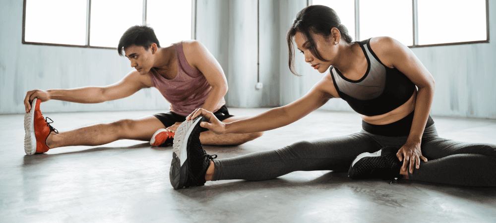 two athletic people performing post workout stretches